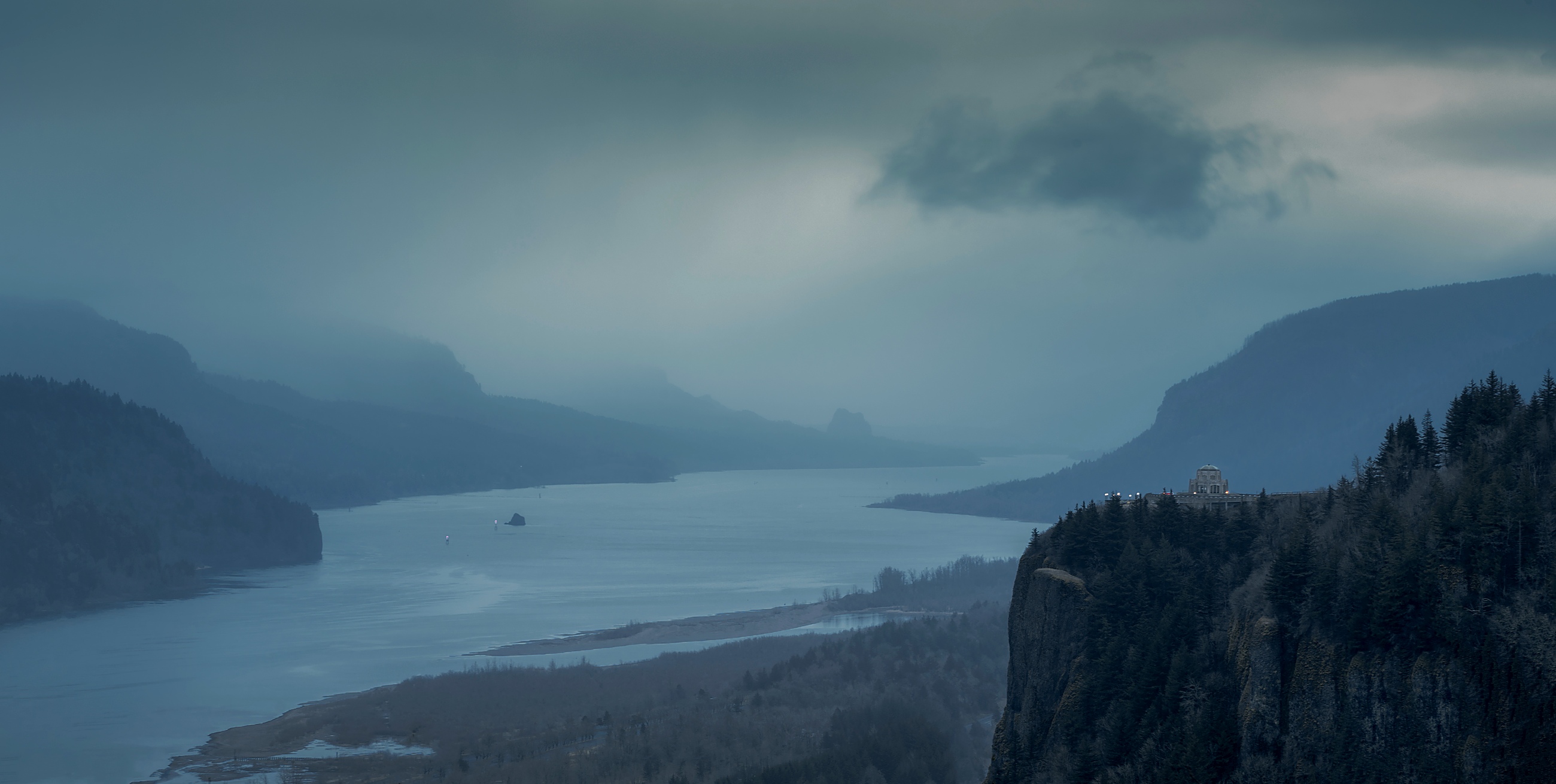 Vista House at Crown Point overlooking a foggy, rain-swept Columbia River Gorge with Beacon Rock dissolving into low cloud